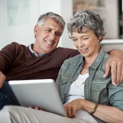 mature couple using a digital tablet while relaxing on their sofa